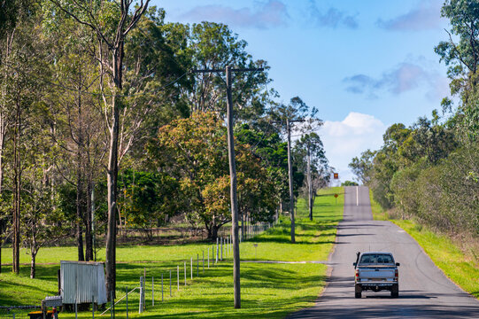 Car moving on asphalt country road with telephone poles and powerlines