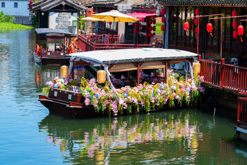 Obraz premium Traditional wooden boat decorated with beautiful flowers moored along a scenic canal in Tongli water town, Jiangsu, China