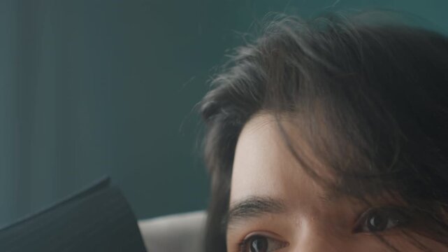 Asian man closeup grooming hair with focused eyes fingers run through dark strands, teal backdrop and implied mirror, micro expressions of calm rehearsal and influencer actor preparation.