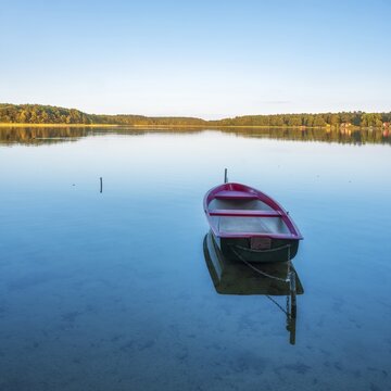Rowing boat moored in the calm waters of a lake in the evening, Wutzsee, Lindow (Mark), Brandenburg, Germany