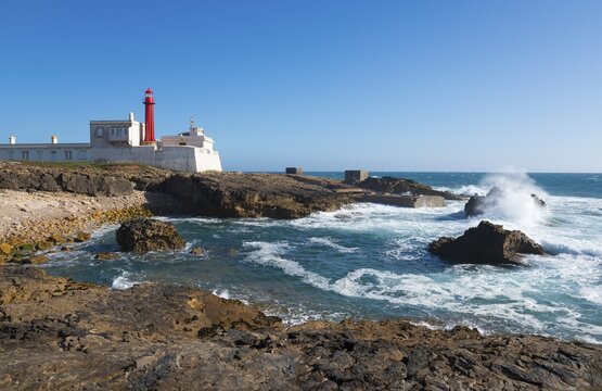 Lighthouse on the coast with rough waves and rocks under a blue sky, Farol do Cabo Raso, S&atilde;o Br&aacute;s de Sanxete fortress, Estoril, Cascais, Parque Natural de Sintra-Cascais, Portugal