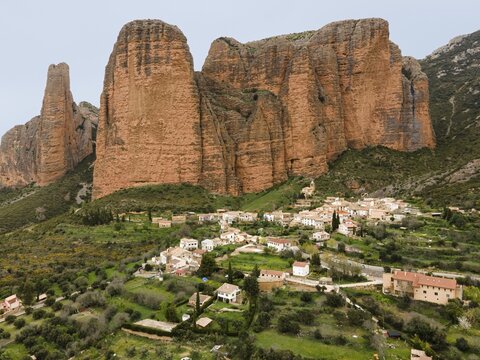View of a small village surrounded by huge rocks and green landscape that gives a quiet and rural feeling, aerial view, Las Pe&ntilde;as de Riglos, As Penyas de Riglos, rock formation Mallos de Riglos, Huesca, Aragon, Spain