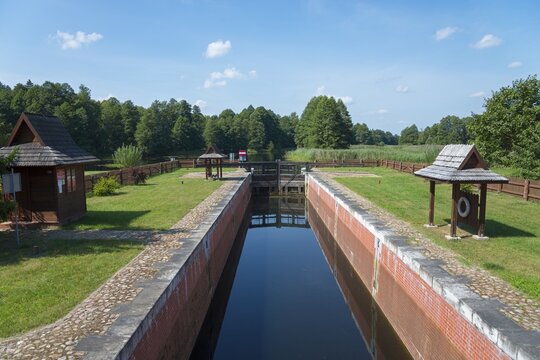 A narrow canal with a lock leads through a green forest landscape, Tartak Lock, Augustow Canal, Augustowski Canal, Suwałki, Podlaskie, Podlaskie, Poland