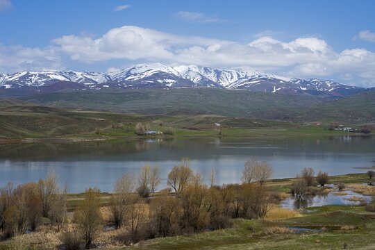 Peaceful landscape with a lake surrounded by snow-capped mountains. Trees and meadows dot the shore under a blue sky with scattered clouds, Imranli Reservoir, İmranlı, Kizilirmak River, Kızılırmak, Sivas Province, Turkey