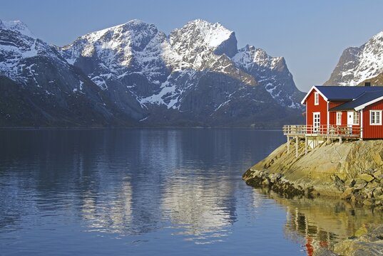Rorbuer and high mountains reflected in a fjord, holiday, tourism, winter idyll, Hamn&ouml;y, Reinefjorden, Lofoten, Norway