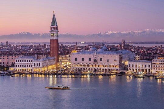 Waterfront with Campanile and Doge's Palace in front of the Alpine chain at dusk, Venice, Veneto, Northern Italy, Italy. UNESCO World Heritage Site