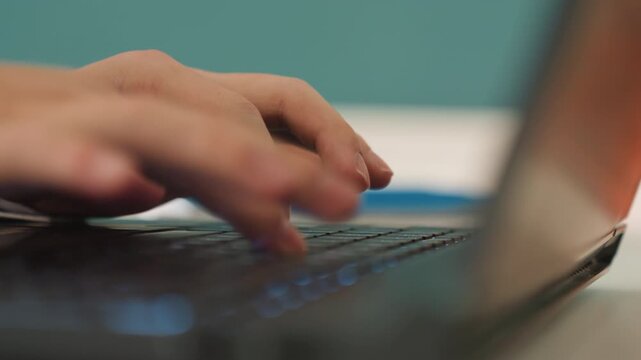 Caucasian hands rapidly coding during night. Closeup of hands typing on keyboard under backlit keys. Closeup of student hands working quickly on laptop during latenight programming session
