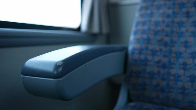 Empty Train Seat Armrest and Window View on a Moving Journey.