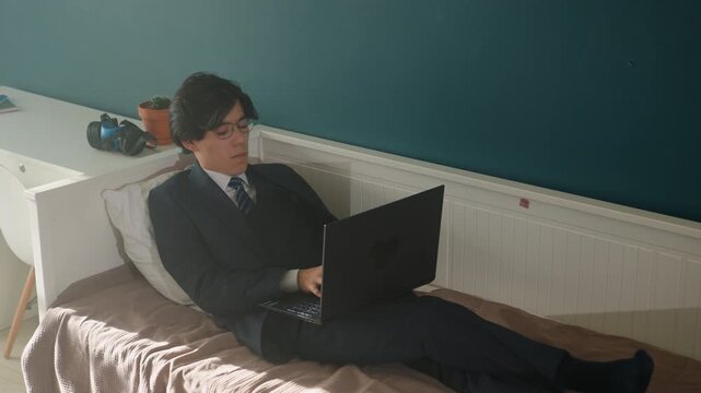 Man in formal wear with laptop at home. Business professional preparing presentation in home office environment. Man dressed in suit focused on laptop while working at home setup near desk