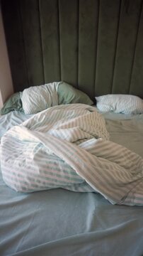 Messy bed with crumpled sheets in bedroom setting