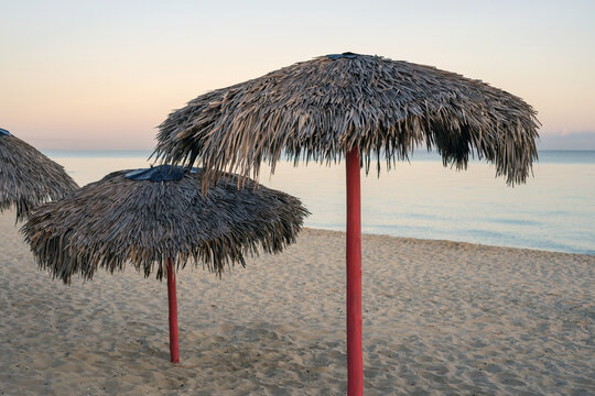 Beautiful view of white sand beach with sun umbrellas from palm leaves. Cuba island.