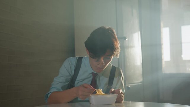 Backlit man eating instant noodles, soft window light and haze create filmic atmosphere, formal shirt with suspenders and tie, slow deliberate slurps, isolated table in apartment kitchen, pensive