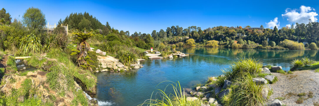 Taupō, New Zealand, panoramic view of famous Otumuheke Stream hot pools, flowing into deep-green crystal-clear Waikato River at Spa Park.