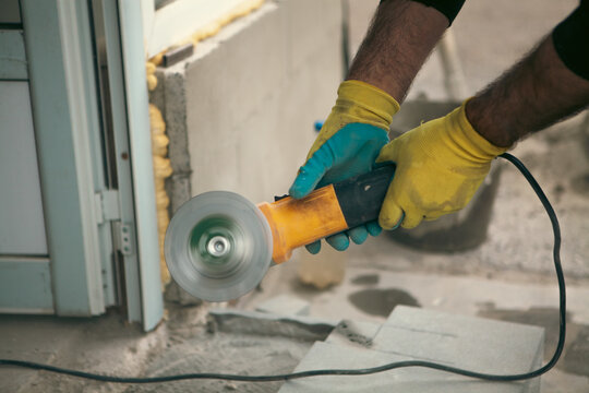 Close-up of worker polishing concrete slab with electric grinder