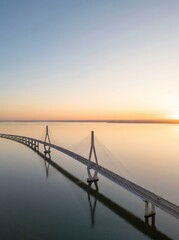 Fototapeta premium [Generative AI] Aerial view of a large cable-stayed bridge over a calm sea at sunset