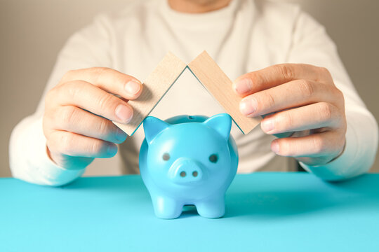 Man holding blue piggy bank with wooden blocks. Saving money concept
