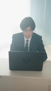 Asian executive working on laptop, focused on screen and documents quiet remote office scene with bright backlight, concentrated typing and spreadsheet review, disciplined routine with soft sunlight,