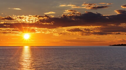 Obraz premium Breathtaking Sunset Over Calm Waters with Dramatic Clouds and Golden Sky Reflections at Dusk in a Tranquil Coastal Environment