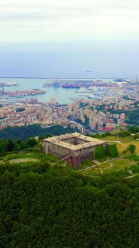 Vertical video. Genoa, Italy. Forte Begato, a 19th-century quadrangular fortress with angular bastions and broad embankments, Drone footage over the Polcevera valley and Ligurian Sea. Drone footage, 