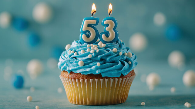 Blue cupcake with frosting and candles with the number 53. The background features soft blue tones and scattered spheres.