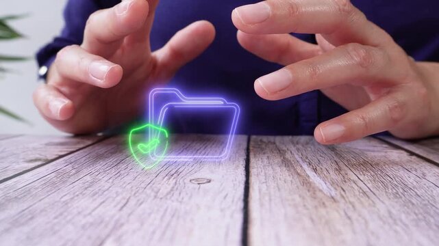 Files verified and protected. Close-up of a person's hands on a table, protecting a virtual folder icon and a shield with a checkmark inside.