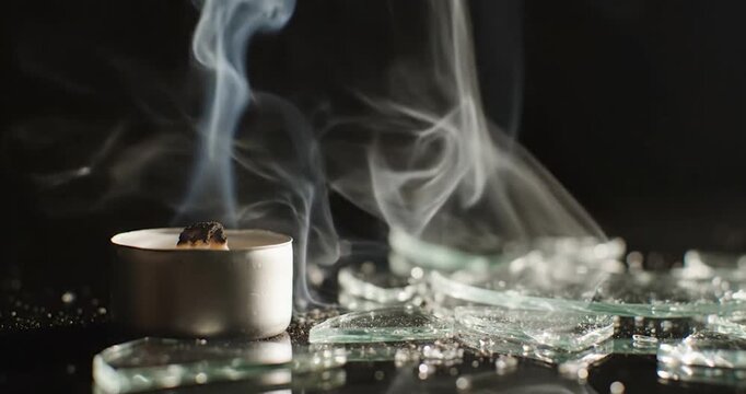 Extinguished Candle With Rising Smoke Near Broken Glass On Black Table