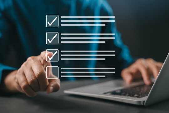 Finger selecting virtual checklist interface, task management planning, business professional executes productivity decision through digital workflow using laptop computer at desk