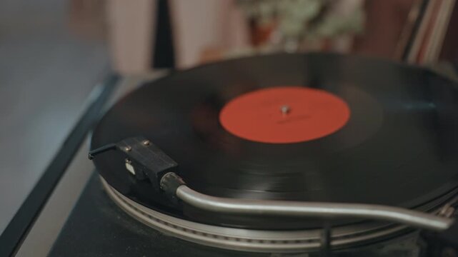 Closeup vinyl record on turntable, warm vintage atmosphere with red label, stylus tracing grooves, ambient light and subtle crackle, cozy living room collector ritual suggesting audiophile listening