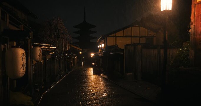 Beautiful rain fall on ancient Japanese village at night with silhouette of tower - steady cam shot