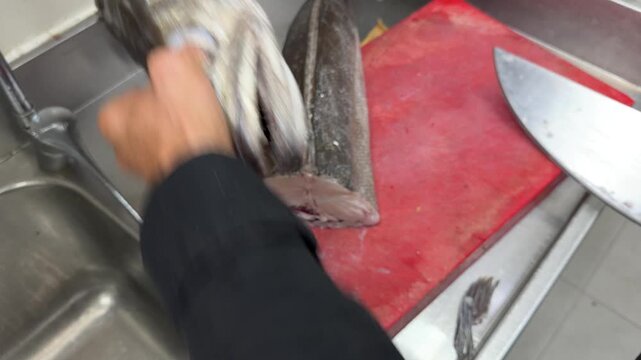 Professional chef cleaning fresh fish in a restaurant kitchen