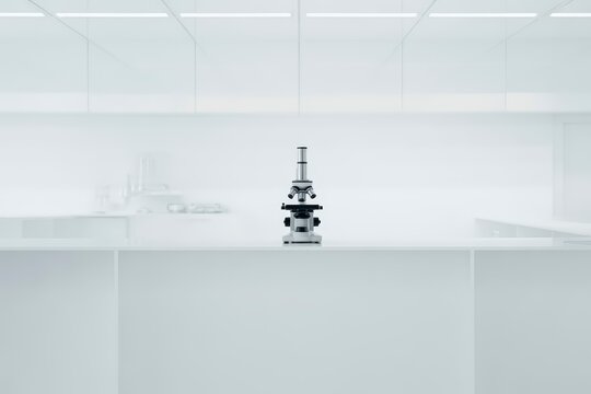 Modern optical microscope standing prominently on a clean white laboratory countertop in a pristine research environment