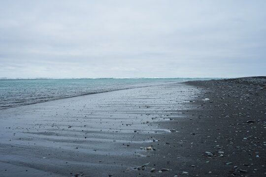 Wet sandy beach with calm sea under overcast sky,Diamond Beach,Iceland