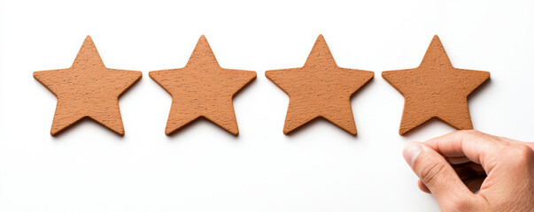Obraz premium hand places the fourth of four wooden star-shaped tokens on a white background, symbolizing rating or review.