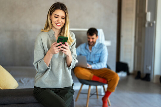 Smiling young female using mobile phone app playing game, shopping online, ordering delivery