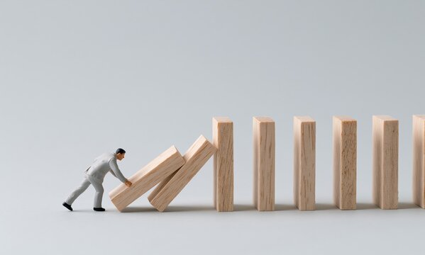 Miniature figure stop wooden blocks domino effect business concept crisis
