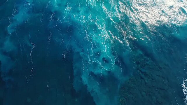 A powerful ocean wave crashes against the deep blue sea surface