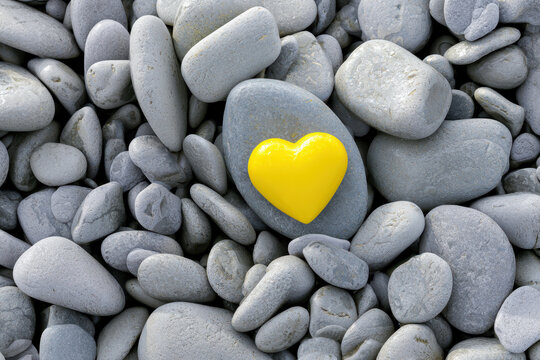Bright yellow heart among gray pebbles