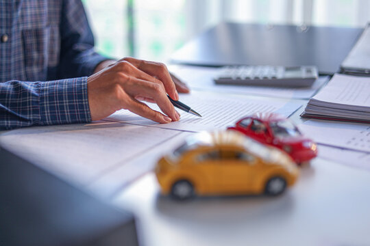 A man signing a contract for a car loan, lease, vehicle registration or insurance policy.&nbsp;Concept for Sales Contract, Financing Agreement, Insurance Policy, Vehicle Registration.