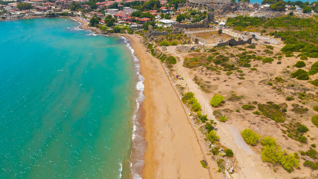 Side, Manavgat, Turkey. Ancient Agora and Roman amphitheater with crane, Temple of Tyche, colonnaded street, beach at archaeological site on sunny day. Aerial View
