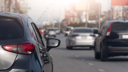Naklejka premium Close-up rear view of a dark grey hatchback waiting in a dense daytime traffic jam. A blurry line of various commuter cars can be seen stretching down the urban street ahead.