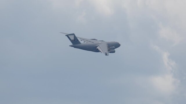 Military cargo aircraft C-17 Globemaster performs airlift operation in cloudy skies