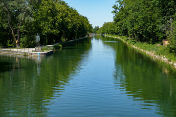 Fototapeta premium View from the Conwentz Bridge on the Isarwerk Canal in Thalkirchen, Munich. The canal leading to the rafting landing site, which runs parallel to the Isar