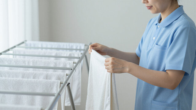 Japanese Female Caregiver Hanging Laundry to Dry in Care Facility, Copy space on the left