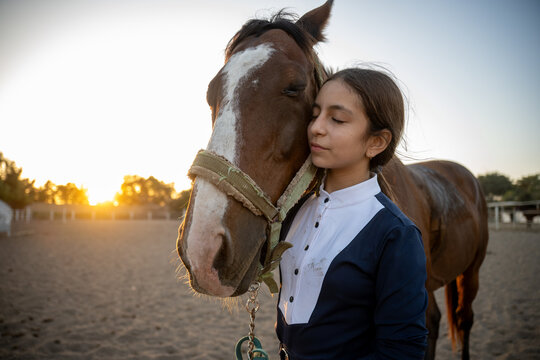 Young girl sharing quiet moment with horse at sunset
