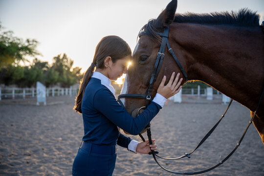 Young rider bonding with horse at sunset
