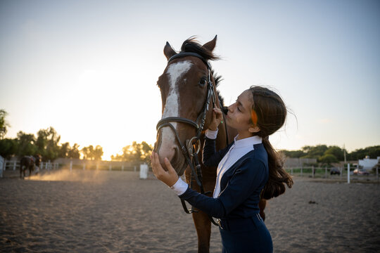 Young rider bonding with bay horse at sunset