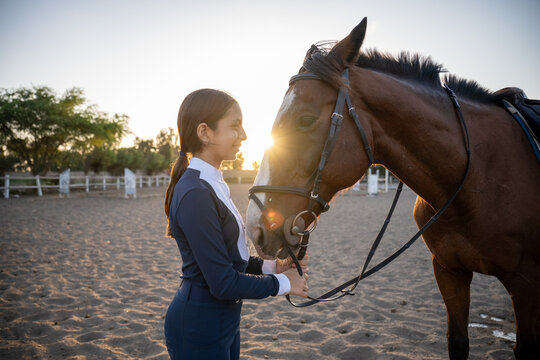 Young rider bonding with bay horse at golden hour