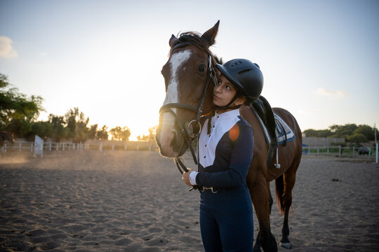 Young equestrian girl bonds with her horse at sunset