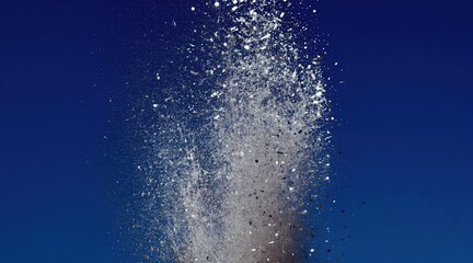 Obraz premium Silver confetti explodes in dynamic burst against deep blue backdrop. Small glittering particles scatter, creating festive abstract motion. Great for party, holiday, or event promotions.