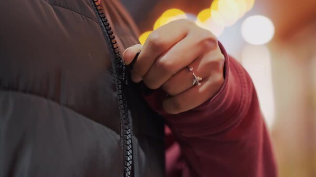 Urban evening readiness. Getting dressed for city night walk. Closeup of hands donning warm attire for night outing. Focusing on urban evening scene with coat and rings before stepping outside